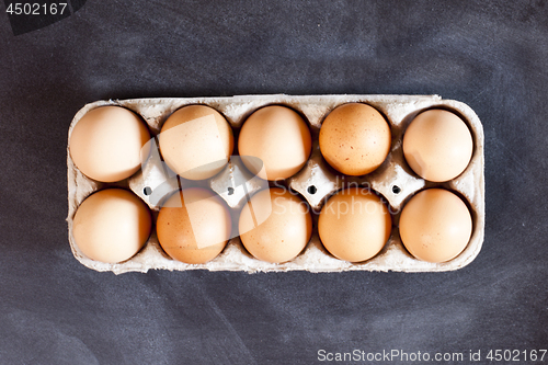 Image of Farm chicken eggs in cardboard container on black background.