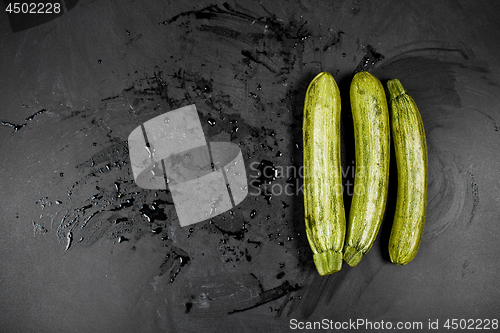 Image of Fresh green wet zucchini on blackboard background. 