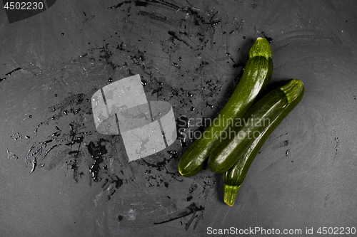 Image of Fresh green wet zucchini on blackboard background. 
