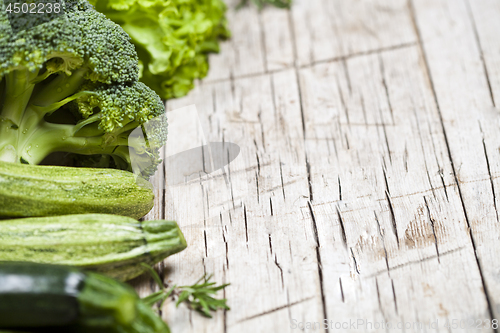 Image of Variety of green vegetables on rustic wooden background. 