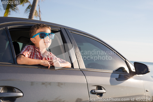 Image of One happy little boy sitting in the car at the day time.