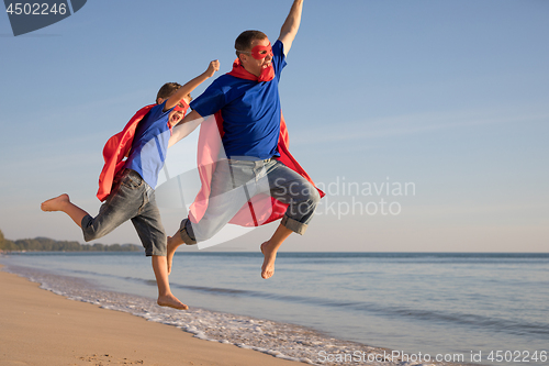 Image of Father and son playing superhero on the beach at the day time.