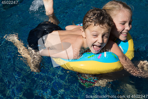 Image of Two happy children  playing on the swimming pool at the day time