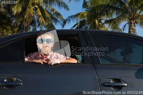 Image of One happy little boy sitting in the car at the day time.