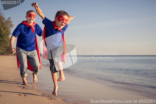 Image of Father and son playing superhero on the beach at the day time.