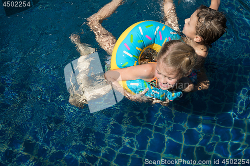 Image of Two happy children  playing on the swimming pool at the day time