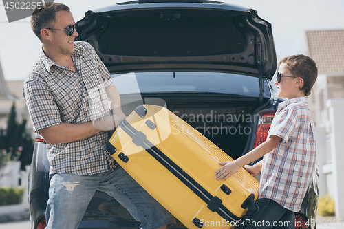 Image of Happy father and son getting ready for road trip on a sunny day.