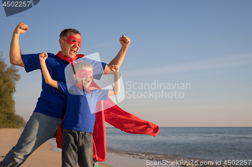 Image of Father and son playing superhero on the beach at the day time.