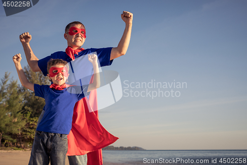 Image of Father and son playing superhero on the beach at the day time.