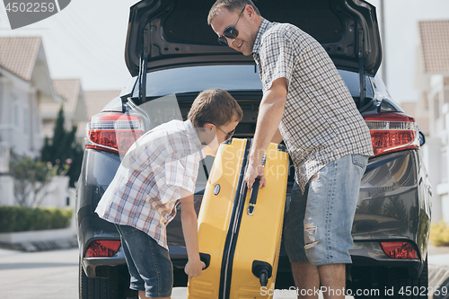 Image of Happy father and son getting ready for road trip on a sunny day.