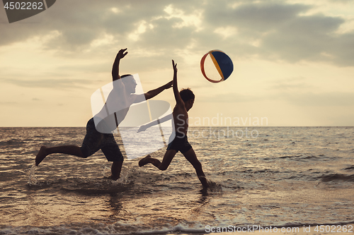 Image of Father and son playing on the beach at the sunset time.