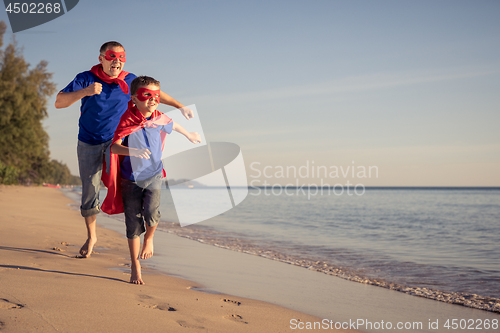 Image of Father and son playing superhero on the beach at the day time.