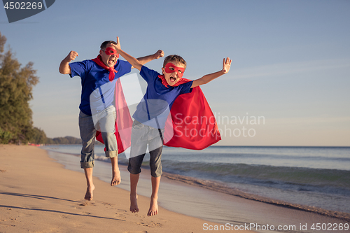 Image of Father and son playing superhero on the beach at the day time.