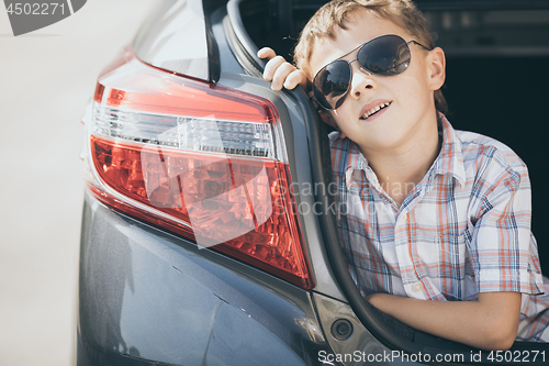 Image of One happy little boy sitting in the car at the day time.