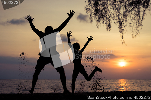 Image of Father and son playing on the beach at the sunset time.