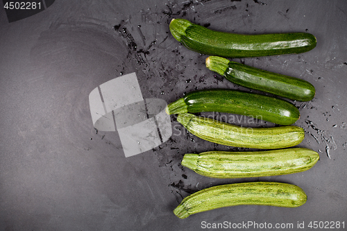 Image of Fresh green wet zucchini on blackboard background.