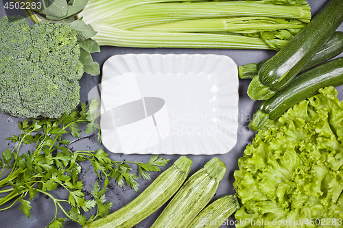 Image of Variety of green vegetables and white ceramic plate. 