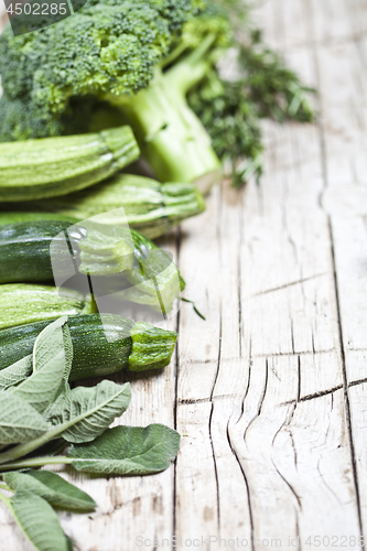 Image of Variety of green organic vegetables on rustic wooden background.