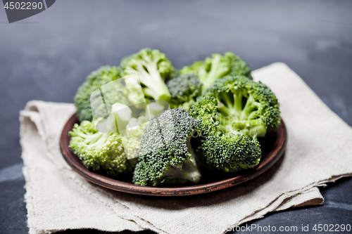 Image of Fresh green organic broccoli in brown plate and linen napkin