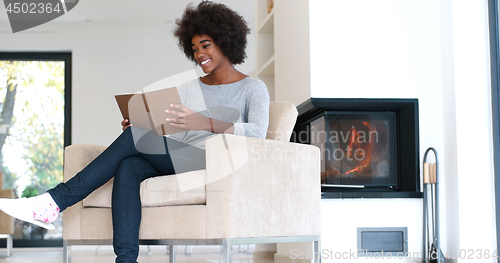 Image of black woman at home reading book