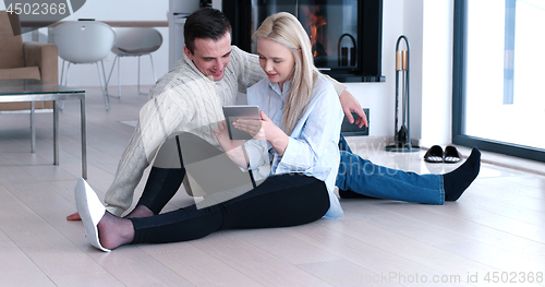 Image of Young Couple using digital tablet on the floor