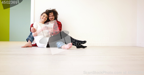 Image of Young Couple using digital tablet on the floor