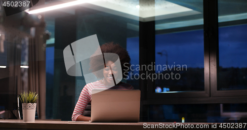 Image of black businesswoman using a laptop in night startup office