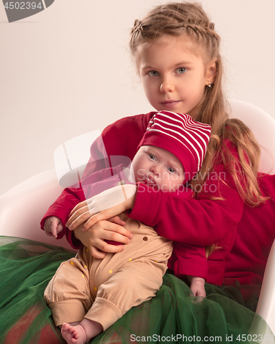 Image of Happy little teen girl holding his newborn baby little sister. Family love.