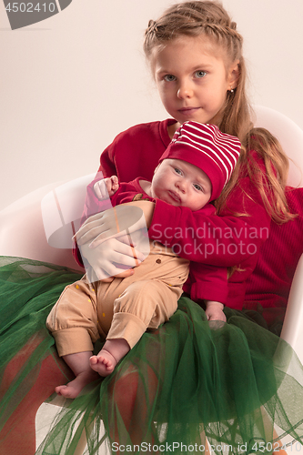 Image of Happy little teen girl holding his newborn baby little sister. Family love.