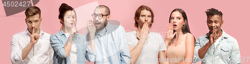 Image of The young men and women whispering a secret behind hands over pink background