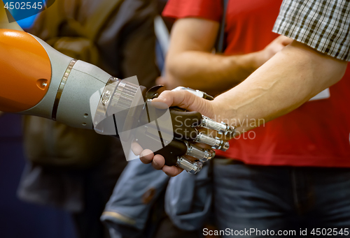 Image of Hand of a man shaking hands with a Android robot.