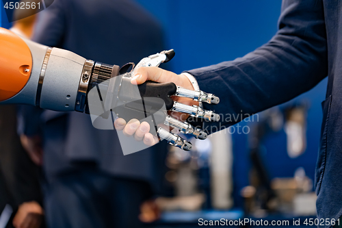 Image of Hand of a businessman shaking hands with a Android robot.