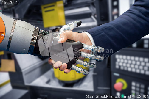 Image of Hand of a businessman shaking hands with a Android robot.