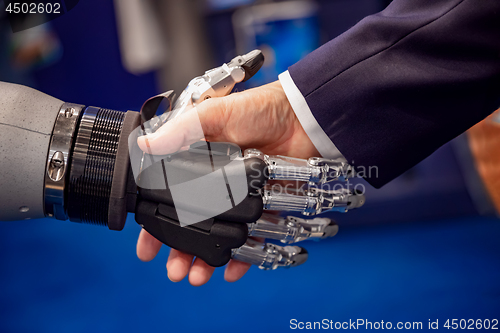 Image of Hand of a businessman shaking hands with a Android robot.