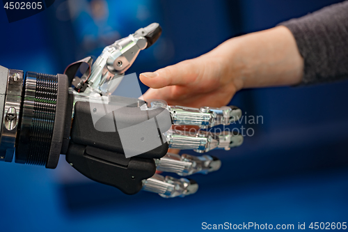 Image of Hand of a businesswoman shaking hands with a Android robot.