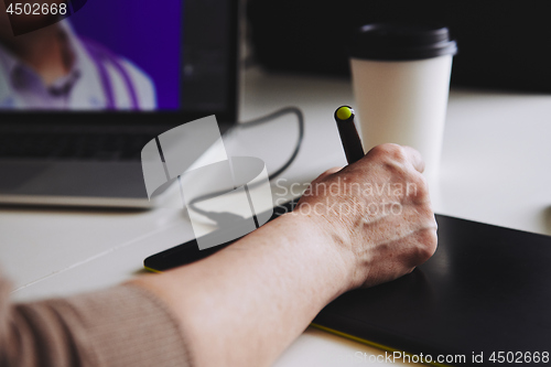 Image of Woman designer working at a laptop with a graphics tablet.