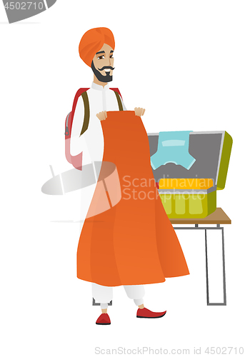 Image of Hindu traveler man packing suitcase.