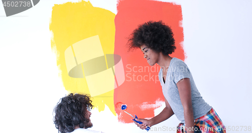 Image of multiethnic couple painting interior wall