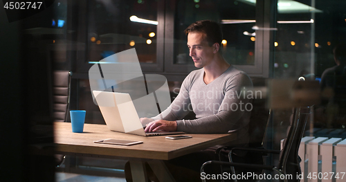 Image of man working on laptop in dark office