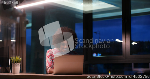 Image of black businesswoman using a laptop in night startup office
