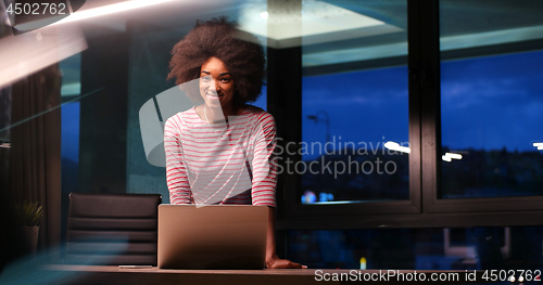 Image of black businesswoman using a laptop in night startup office