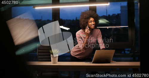 Image of black businesswoman using a laptop in night startup office