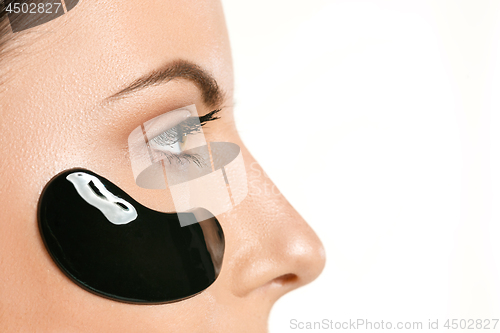 Image of Young beautiful woman applying a mask for the face of the therapeutic black mud. Spa treatment