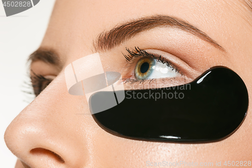 Image of Young beautiful woman applying a mask for the face of the therapeutic black mud. Spa treatment