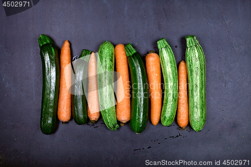 Image of Fresh organic wet carrots and zucchini on black background. 