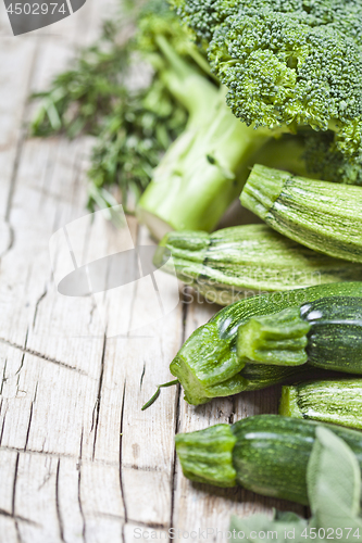 Image of Variety of green organic vegetables on rustic wooden background.