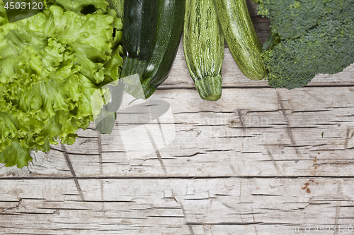 Image of Variety of green organic vegetables on rustic wooden background.