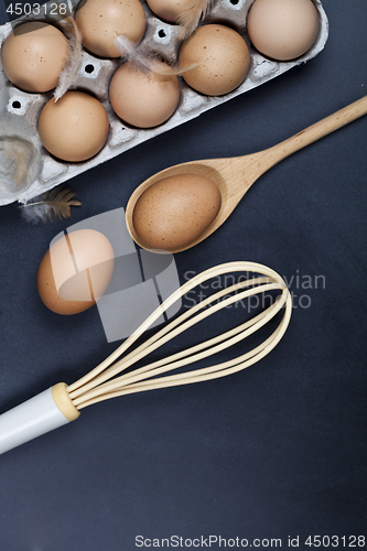 Image of Eggs, wooden spoon, whisker and feathers. Kitchen utensil for ca