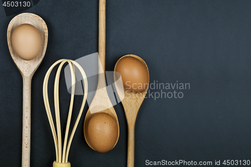 Image of Eggs, wooden spoon and whisker. Kitchen utensil for cake, pastry