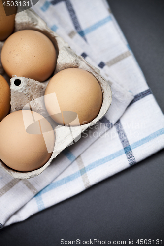 Image of Fresh organic eggs in cardboard box an linen towel closeup on ba